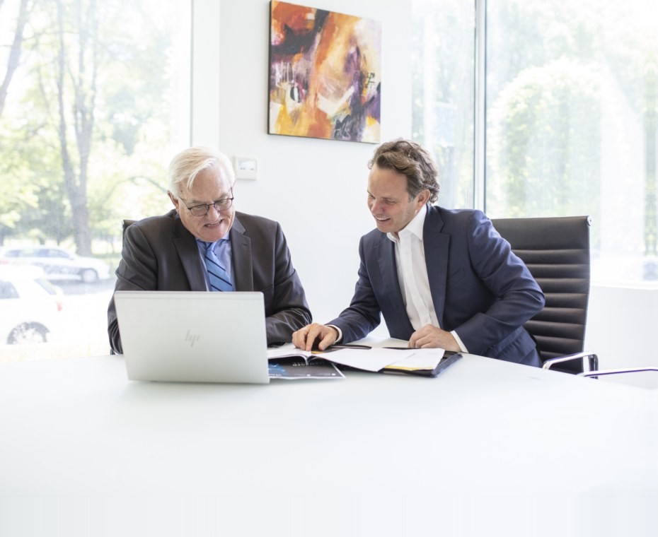 Two people talking through a document at a laptop in a meeting room