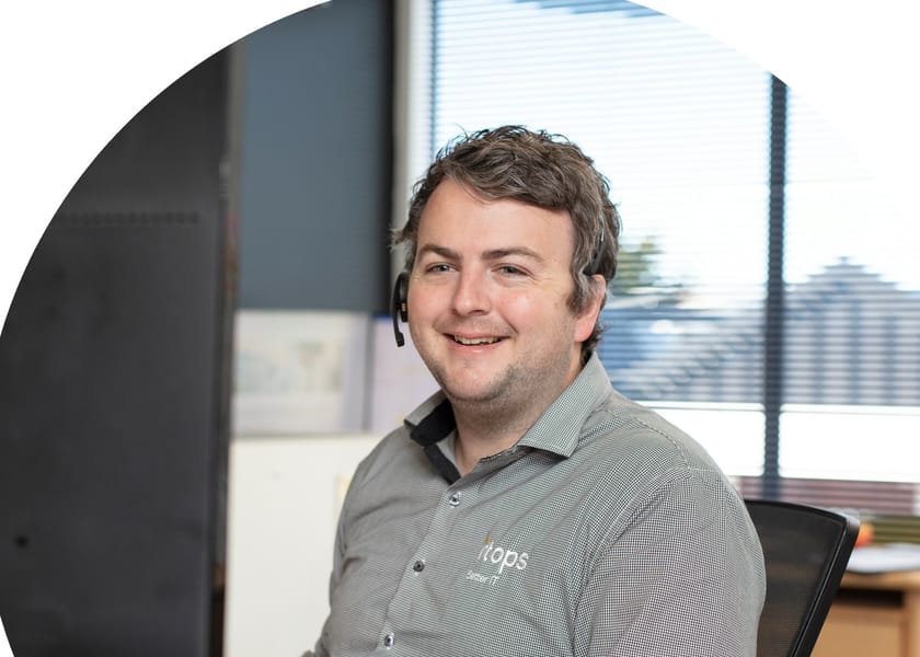 An iTops engineer wearing a headset, working at his desk