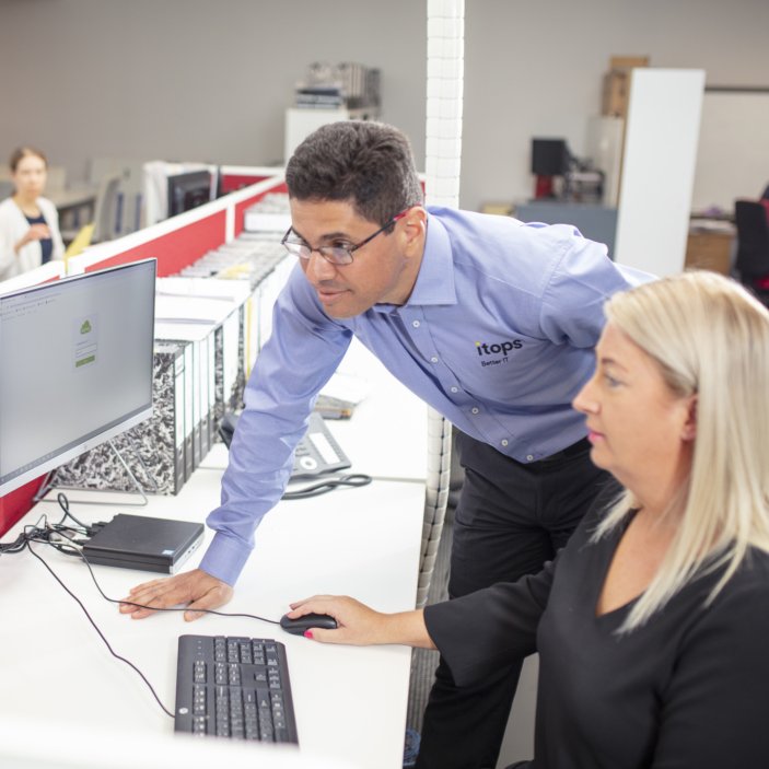 An iTops engineer working with a client at her desk